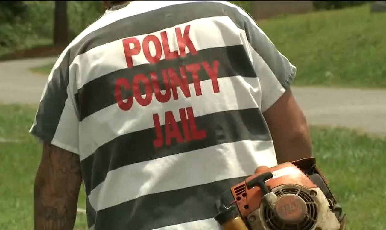 An inmate from the Polk County Jail wearing a black-and-white striped work-detail uniform while carrying a gas-powered outdoor tool, Photo Credit: 11Alive/Youtube