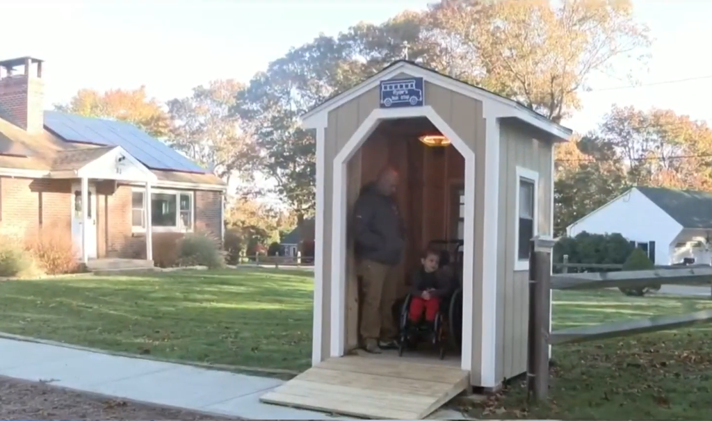 Ryder Kilam with his dad inside a sheltered bus stop shed constructed by the Construction Technology class at Westerly High School, Photo Credit: Click On Detroit | Local 4 | WDIV/Youtube