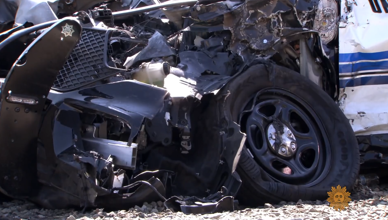 A heavily damaged front end of a black-and-white police cruiser involved in a severe vehicular collision, Photo Credit: CBS Sunday Morning/Youtube