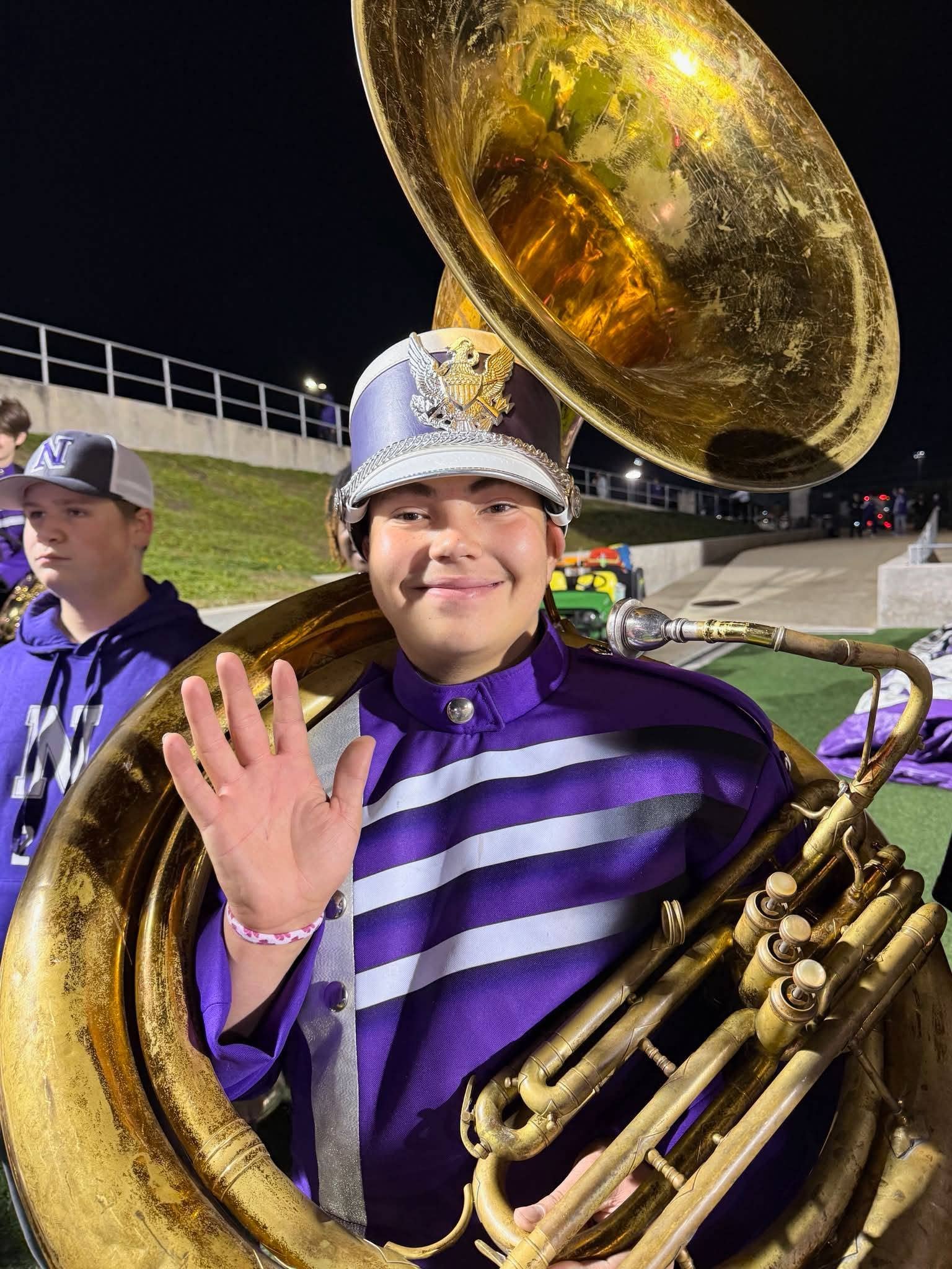 Kinden Washington wearing a purple and white marching band uniform while holding a large sousaphone, Photo Credit: 12NewsNow/Youtube