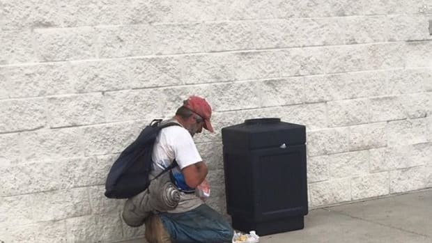 man looking for food in trash can