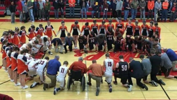 a high school basketball team praying at a game