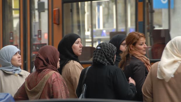 Women wearing headscarves wait for a bus