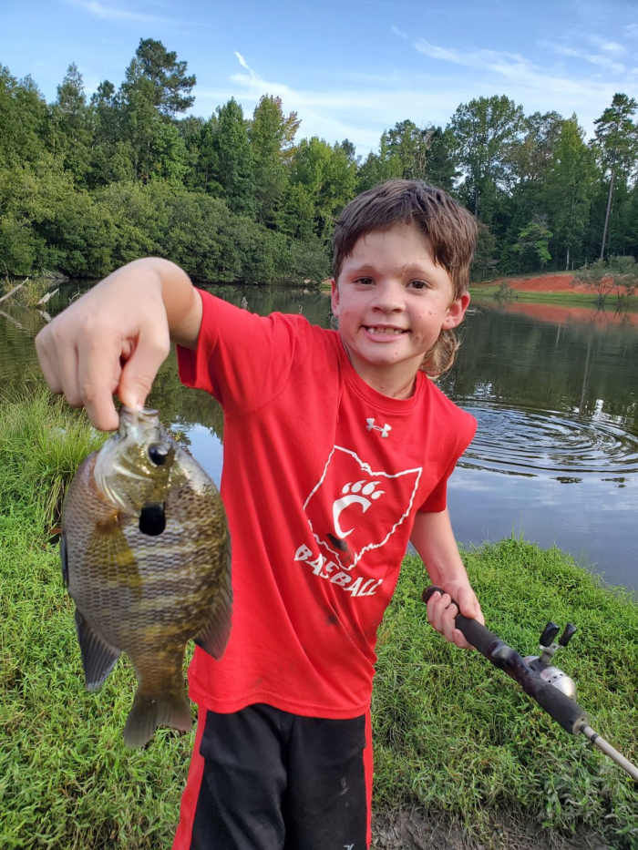 Dylan holding a fish he caught up to the camera smiling, Photo Credit: Facebook/Dylan's Amazing Journey