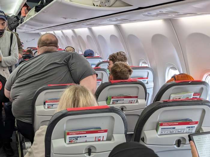 A man struggling to fit in his seat inside a plane due to his body weight, Photo Credit: Christopher Elliott/Facebook