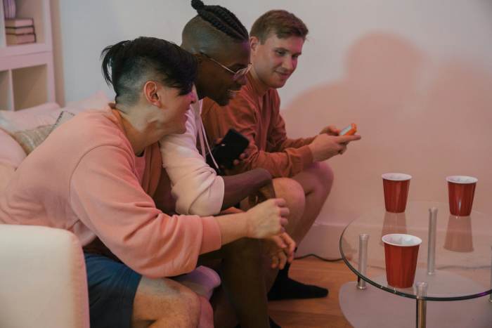 Men Sitting on a Couch Smiling, Talking and Drinking, Photo Credit: Pexels