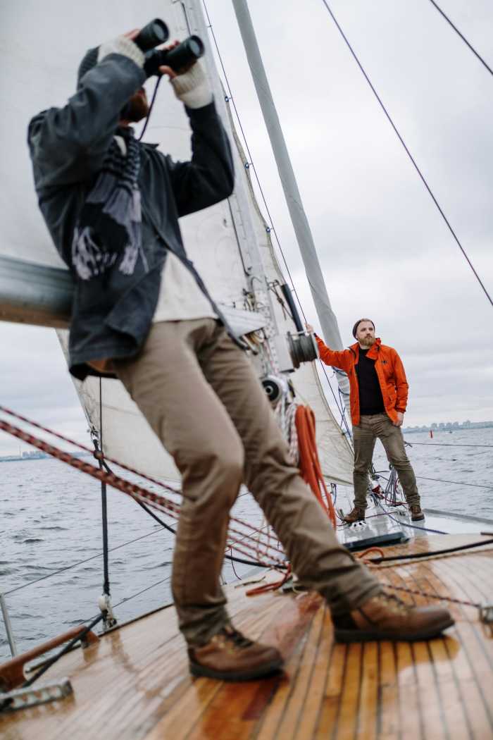 Man Leaning Against a Sail and Looking Through Binoculars, Photo Credit: Pexels