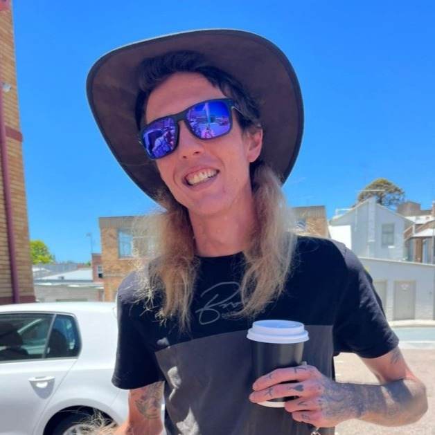 Dylan Watts holding a coffee while wearing a hat and sunglasses , Photo Credit: Gofundme