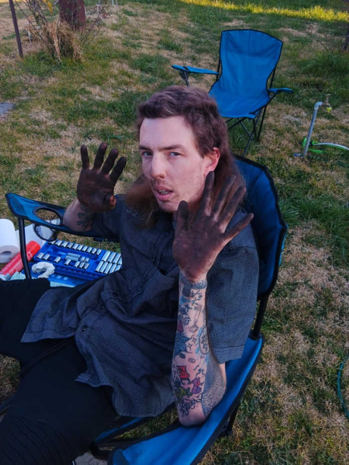 Dylan Watts holding up his hands covered in a black substance, Photo Credit: Gofundme