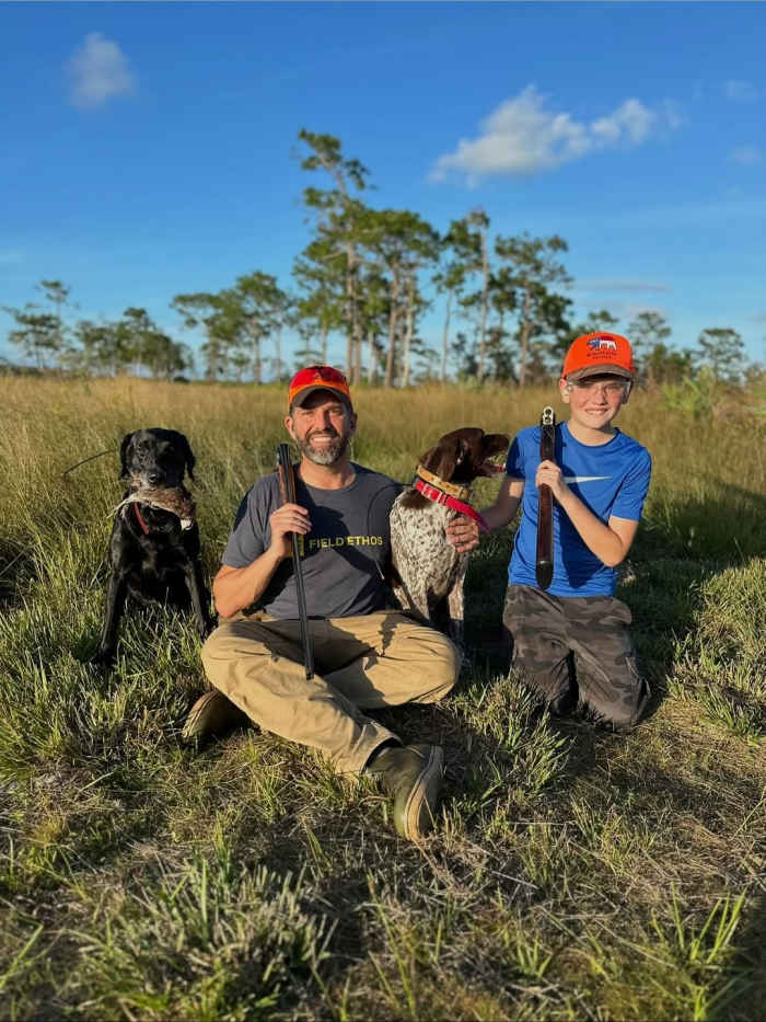 Donald Trump Jr. with his son Spencer holding guns and sitting with their dogs, Photo Credit: donaldjtrumpjr/Instagram
