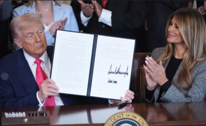 President Trump holding up a signed executive order next to his wife Melania, Photo Credit: louis daniel/X