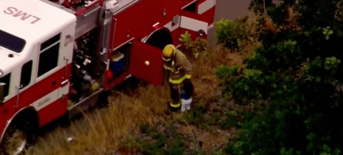 California firefighter comforting a young girl next to a fire truck, Photo Credit: KNSD