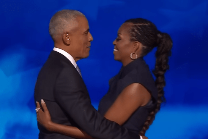 Michelle and Barack Obama hugging on a stage, Photo Credit: Inside Edition/Youtube