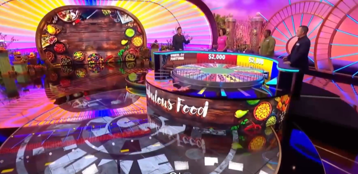 On the set of Wheel of Fortune with contestants and host Ryan Seacrest visible, Photo Credit: Reddit