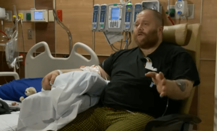 A man sitting down in a hospital room, Photo Credit: Your Living Manna/Youtube