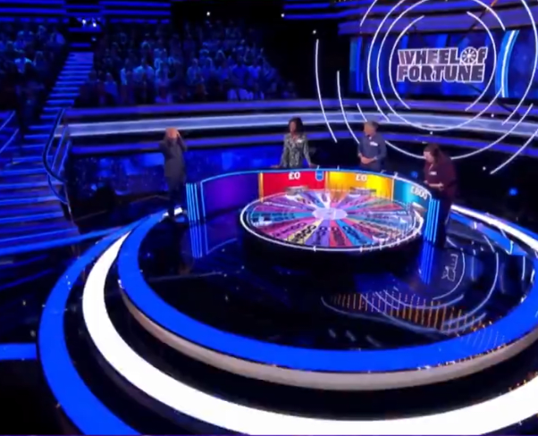 Graham Norton in the studio alongside players Yemi, Richard and Aimee for an episode of Wheel of Fortune UK, Photo Credit: Wheel of Fortune UK/X