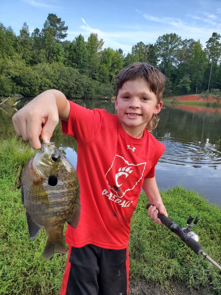Dylan holding a fish he caught up to the camera smiling, Photo Credit: Facebook/Dylan's Amazing Journey