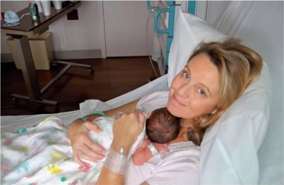 Carolyn Savage smiling at the camera with a newborn in her arms in the hospital, Photo Credit: Viral Stories/Youtube