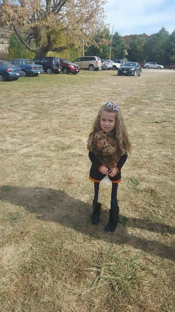 Viral image of a little girl standing on grass where her legs look extremely skinny but that's only because she's holding a bag of popcorn which creates an optical illusion,  Photo Credit: BIG 101/Facebook