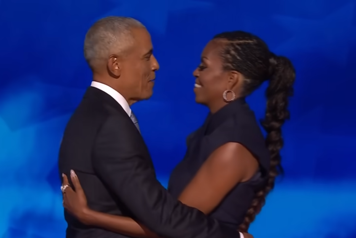 Michelle and Barack Obama hugging on a stage, Photo Credit: Inside Edition/Youtube