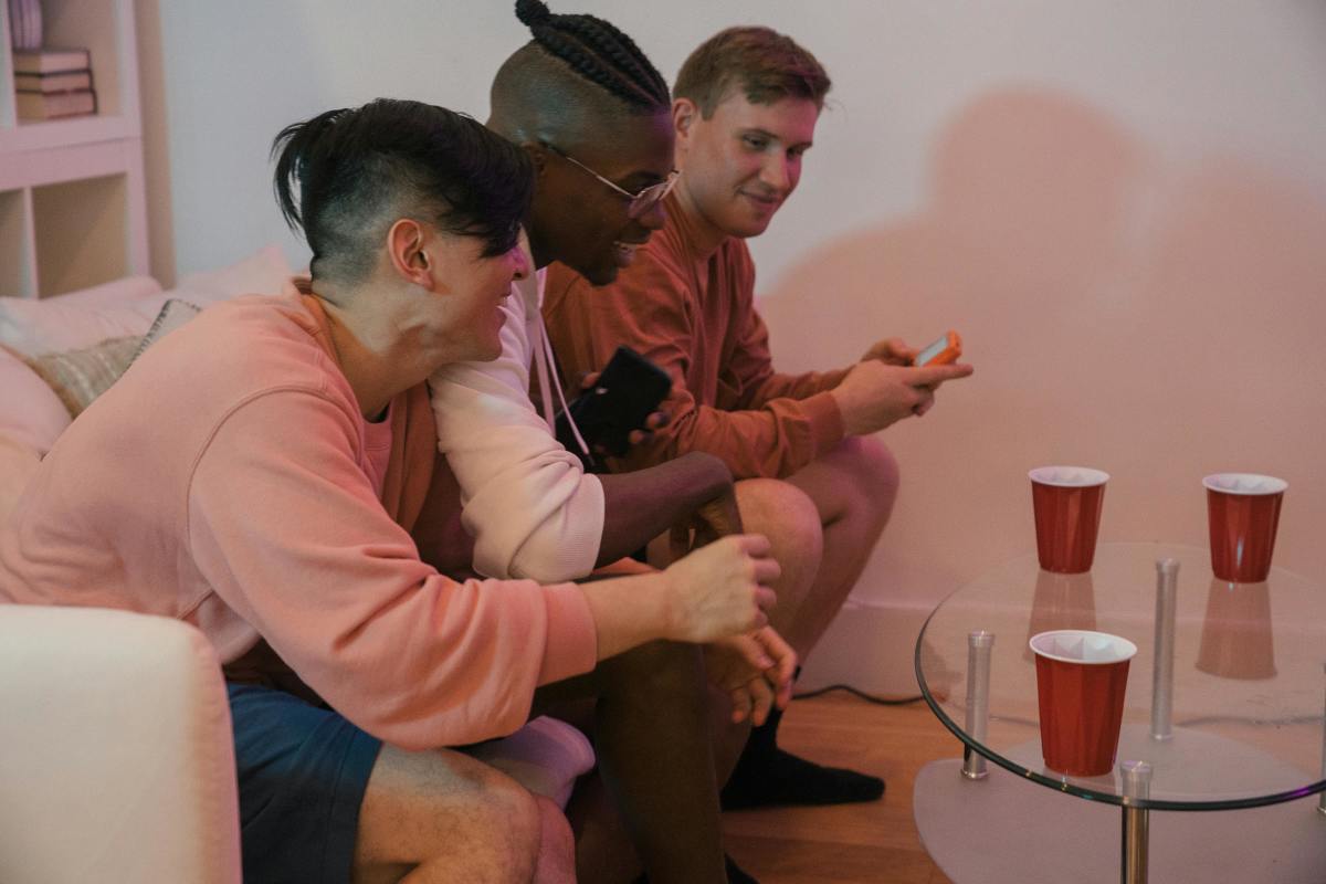 Men Sitting on a Couch Smiling, Talking and Drinking, Photo Credit: Pexels
