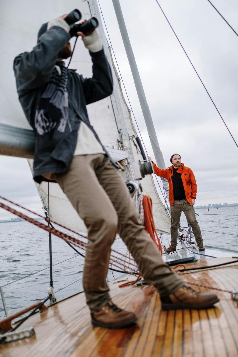 Man Leaning Against a Sail and Looking Through Binoculars, Photo Credit: Pexels