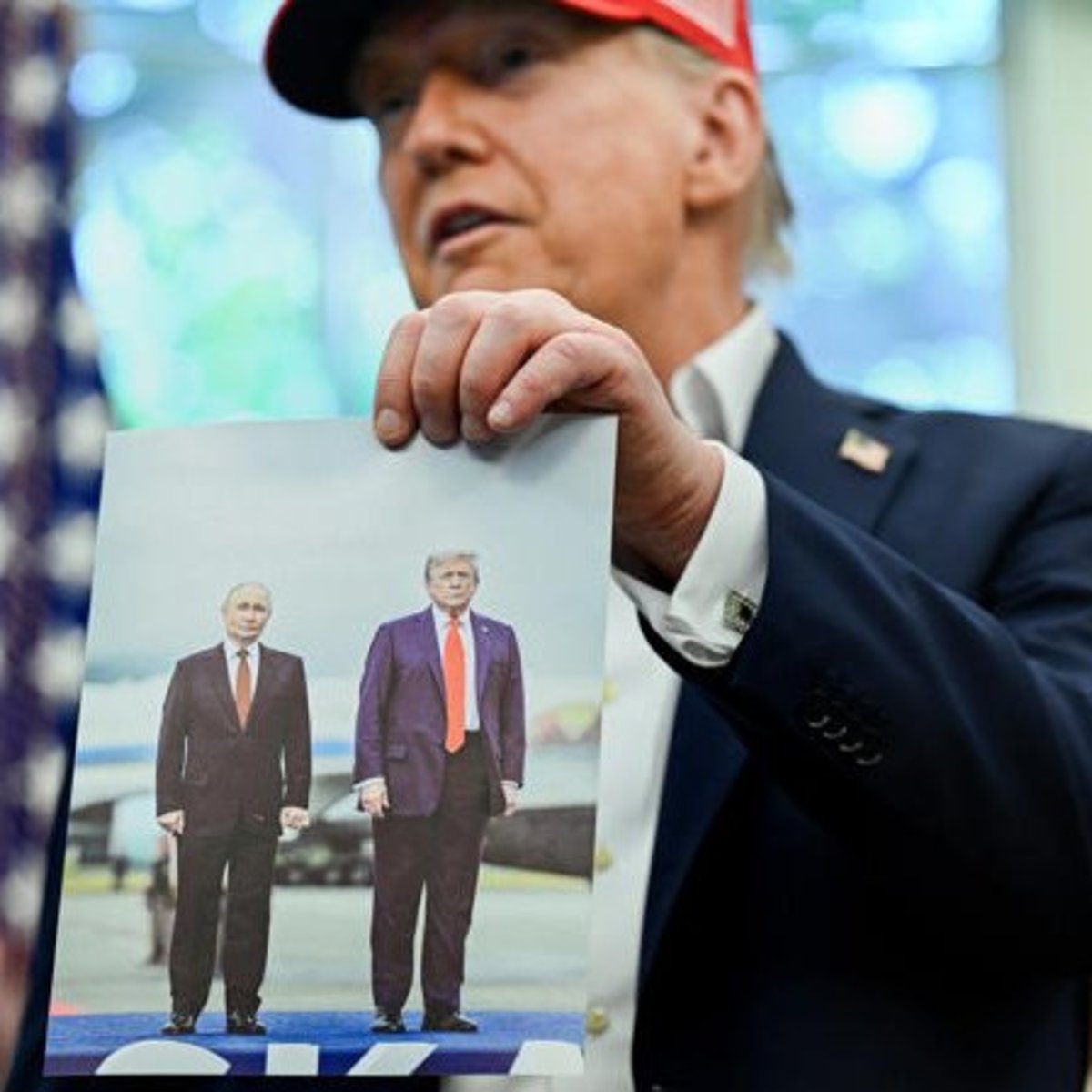 US President Donald Trump holding a photo of him and Russian President Vladimir Putin during their meeting in Alaska, Photo Credit: DonkConnects/X
