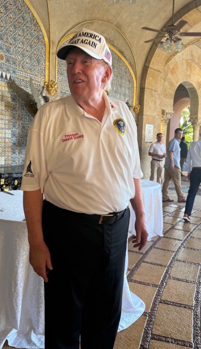 President Donald Trump at Mar-a-Lago wearing a white polo shirt and Make America Great Again hat, Photo Credit: Lucas Sanders/X