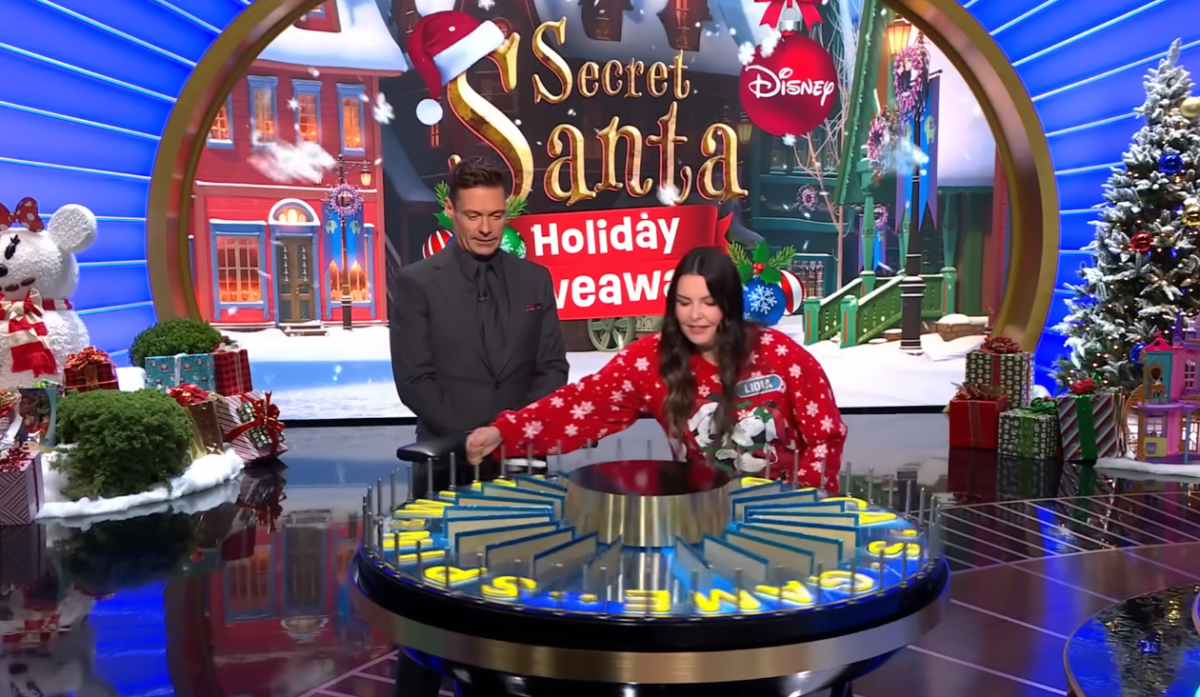 Contestant Lidia Abbott spinning the wheel beside host Ryan Seacrest, Photo Credit: Wheel of Fortune/Youtube