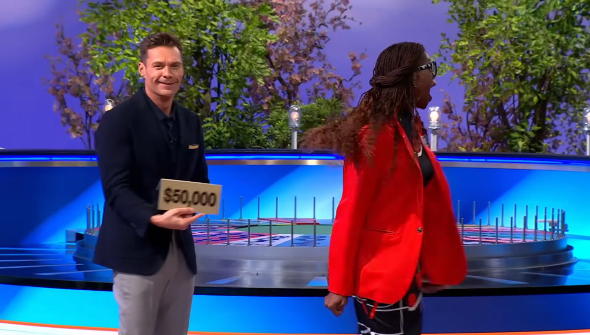 Host Ryan Seacrest standing next to a celebratory Traci Demus-Gamble, Photo Credit: Wheel of Fortune/Youtube