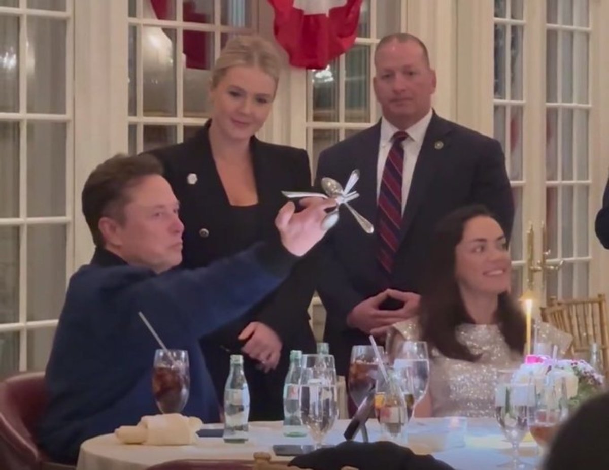 Elon Musk playing with cutlery while sitting at a table with Shivon Zilis, Photo Credit: MIKDUB/X