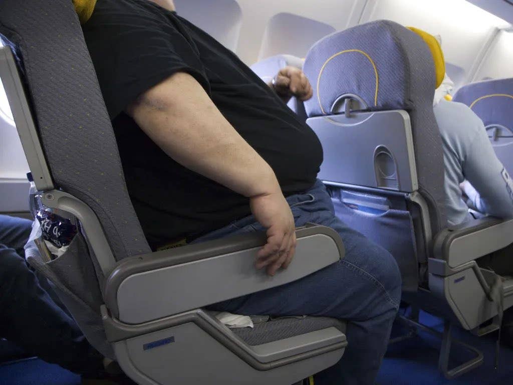 A plus size man sitting on a plane, Photo Credit: Nick Sortor/X