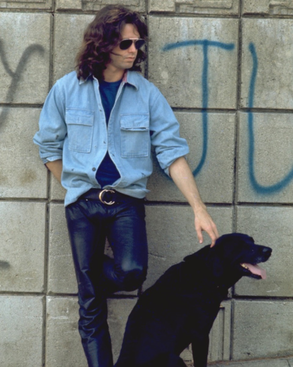 Jim Morrison posing with a black dog in the street, Photo Credit: Jim Morrison /Facebook